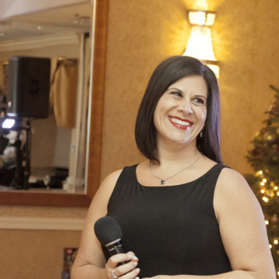Nicole Comis speaking confidently on stage at the DuPage County Toys for Tots Gala, a charity event she hosted.
