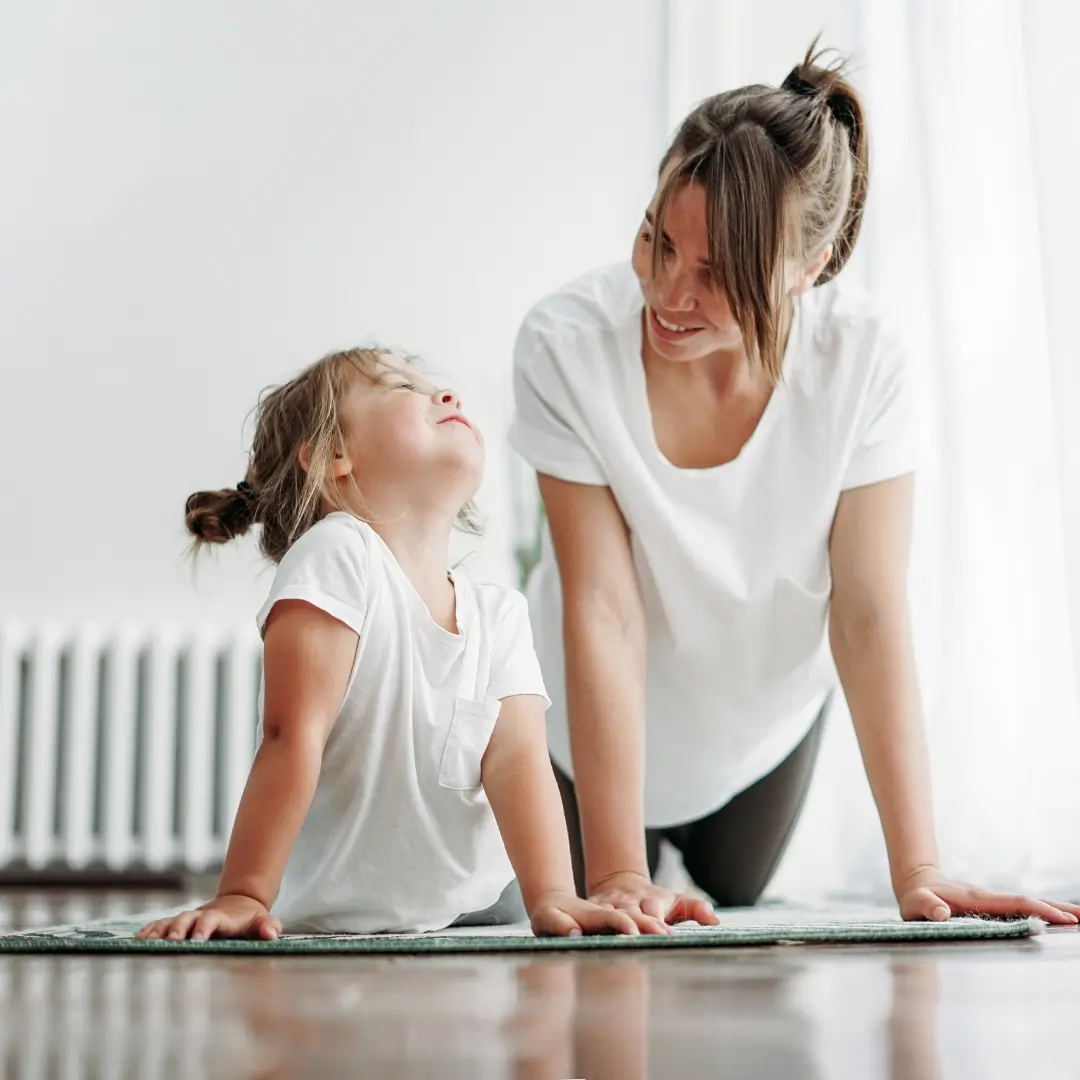 Mother and daughter practicing yoga together, symbolizing the power of leading by example in daily life
